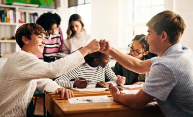 student in classroom with fist bump, success and collaboration