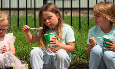 five kids sit on a curb eating 