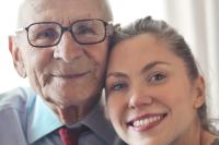 Happy senior man and young adult woman hugging and smiling