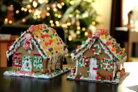 Two decorated gingerbread houses with a Christmas tree in the background.