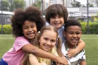 ethnically diverse children hugging each other in a park