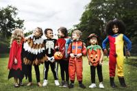 seven children dressed up in various Halloween costumes in a grass field