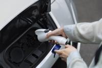 Woman holding charge port to charge her electric vehicle 