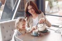 Mother serving young daughter tea from a tea pot 