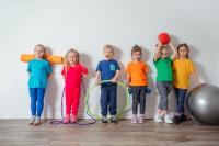 six smiling children lined up against a wall with fitness equipment
