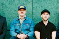 four members of the band jigjam pose on a wall