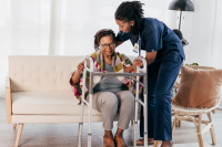 female nurse supporting a female senior with a walker at home 