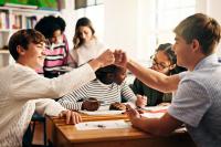 student in classroom with fist bump, success and collaboration