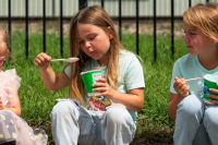 five kids sit on a curb eating