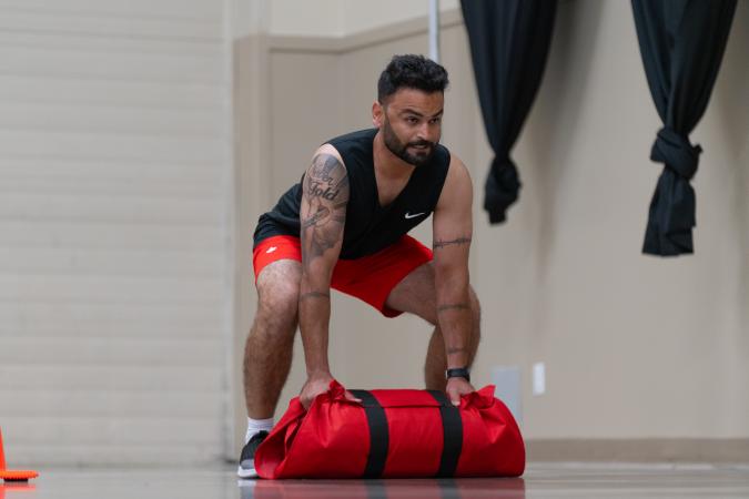 Individual carries red weighted bag during PARE training