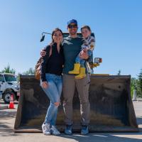 a family poses in front of a front loader 