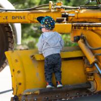 a young kid looks over the blade of a snow grater 