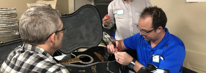 Repair Cafe volunteers fixing a musical instrument - guitar
