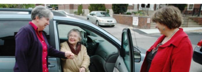 Volunteer women helping lady get out of the vehicle
