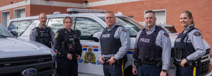 Members of Okotoks Municipal Enforcement and RCMP stand in front of a police car