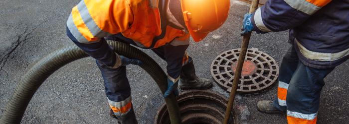 worker in orange high visibility vest working on sewer main