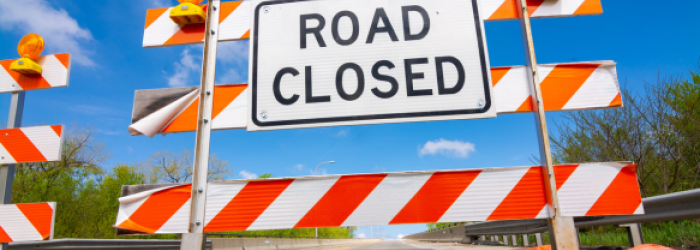 Orange road closed sign with blue sky in background