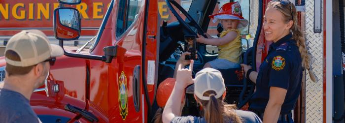 Okotoks Fire fighter stands in front of fire truck at emergency preparedness week open house 
