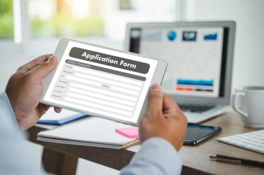 Person holding a tablet submitting an online application form