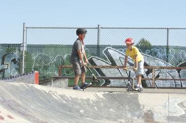 two kids on scooters at Okotoks skate park