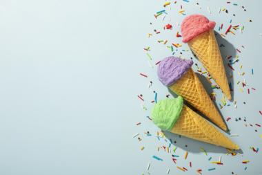 colourful ice cream cones surrounded by sprinkles with a light blue background