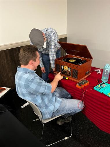 Repair Cafe volunteer fixing old record player