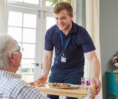 male senior and male nurse providing home care and a meal 