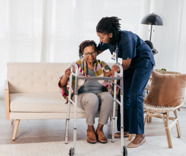 female nurse supporting a female senior with a walker at home 