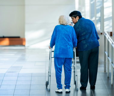 senior woman walking with a walker/walking device with assistance